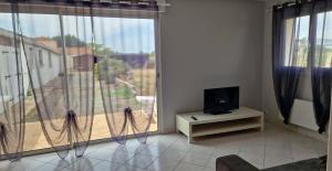 a living room with a tv and a large window at L'escapade in Rétaud