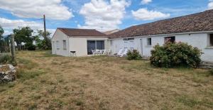 a white house with chairs and a yard at L'escapade in Rétaud