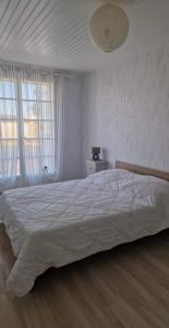a white bedroom with a large bed and two windows at L'escapade in Rétaud