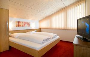 Schlafzimmer mit einem Bett mit weißer Bettwäsche und einem TV in der Unterkunft Apart Marienberg in Lermoos