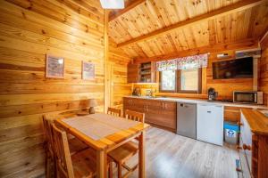 a dining room with a table and a kitchen in a cabin at Osada nad Wdą w Borsku in Borsk