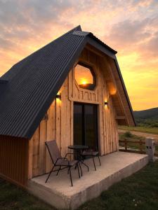 a cabin with a table and chairs in front of a sunset at Alvearium Chalets in Žabljak