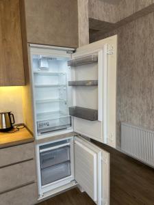 an empty refrigerator with its door open in a kitchen at GM Apartment in Tbilisi City