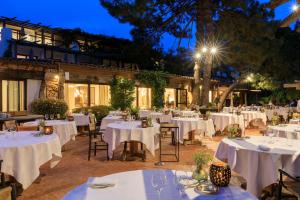 a restaurant with white tables and chairs at night at Grand Hôtel De Cala Rossa & Spa Nucca in Porto-Vecchio