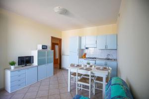 a kitchen with blue cabinets and a table with chairs at Residence Smith Sul Mare in Lido degli Estensi