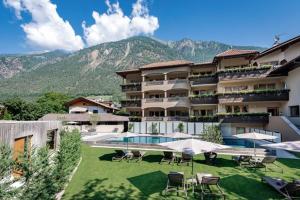 a large building with a swimming pool and chairs at Hotel Kesslwirt in Ciardes