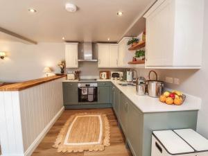 a kitchen with green cabinets and a wooden floor at Captains Barn in Tiverton +15 photos