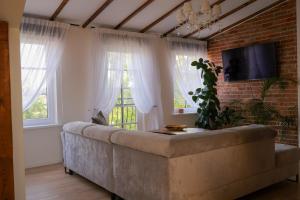 a living room with a large couch and windows at Pliusas Residence in Jurbarkas