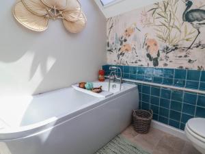 a bathroom with a tub and a toilet at Captains Barn in Tiverton