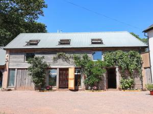 an old house with a tin roof on a driveway at Captains Barn in Tiverton