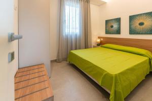 a bedroom with a green bed and a window at VILLA TASSO 25 BILO in Lido degli Estensi
