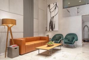 a lobby with a couch and two green chairs at Hotel Brasil 21 Suites, Affiliated by Meliá in Brasília +105 photos