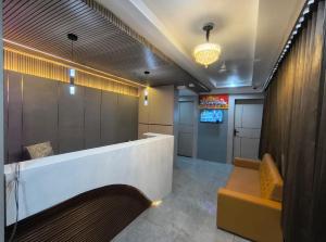 a lobby with a waiting room with a bench and a tv at Hotel Satyam in Vadodara