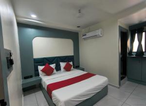 a bedroom with a large bed with red pillows at Hotel Satyam in Vadodara +5 photos