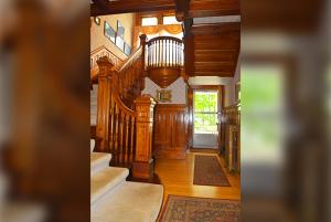 a living room with wooden stairs and a hallway at Cornerstone Victorian Bed and Breakfast in Warrensburg