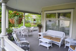 a porch with white chairs and tables on a house at Cornerstone Victorian Bed and Breakfast in Warrensburg