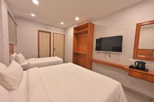a hotel room with two beds and a flat screen tv at CR RIVERA in Madurai +14 photos