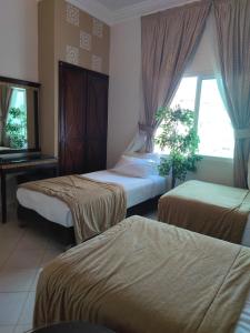 a bedroom with two beds and a window and a table at Hotel Maamoura in Casablanca