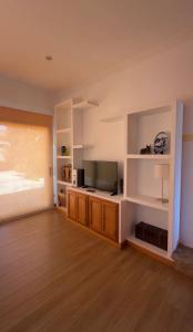 a living room with a flat screen tv and a wooden floor at Villa Aldán Areacova in Aldán