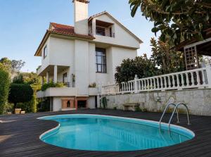 a villa with a swimming pool in front of a house at Villa Aldán Areacova in Aldán