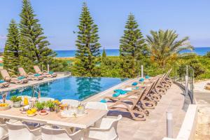 a pool with a table and chairs and the ocean at Villa Vasilissa in Argaka