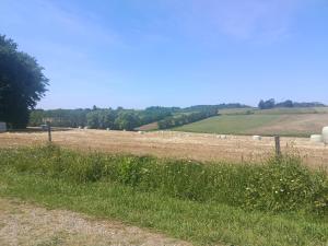 a field with hay bales in the distance at Appartement Mugron in Mugron