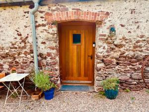 a wooden door of a stone building with a table at The Old Cowshed - B and B in Pembroke