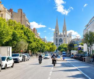 two people riding motorcycles down a city street with a cathedral at Hôtel Faculté in Marseille