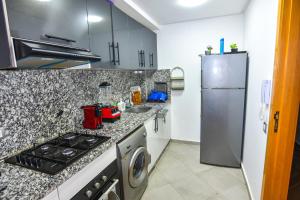 a kitchen with a stove and a refrigerator at Martil , Lieu tranquille avec piscine in Martil