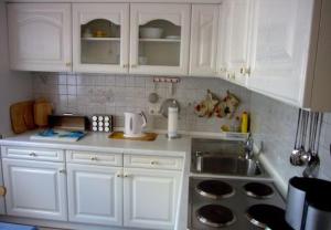 a kitchen with white cabinets and a sink at Apartment kleine Robbe in Büsum