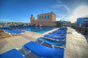 a row of blue lounge chairs next to a swimming pool at Vivaldi Hotel in St. Julianʼs