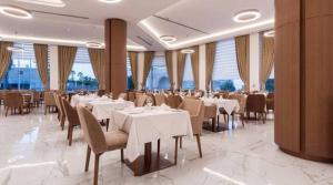 a restaurant with white tables and chairs and windows at Vivaldi Hotel in St. Julianʼs
