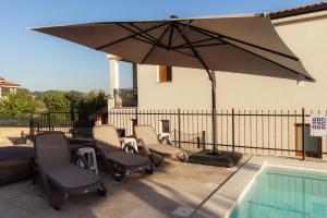 a patio with chairs and an umbrella next to a pool at Villa Lea Marezige Heated Pool near Koper in Marezige