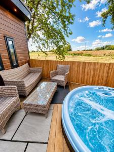 a hot tub on a patio with wicker furniture and a fence at Hideaway by Liv Retreats in Lincoln