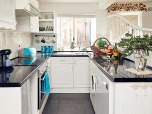 a kitchen with white cabinets and a black counter top at Apple Bough Cottage in Hereford