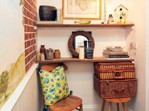 a shelf in a hallway with baskets and a chair at Apple Bough Cottage in Hereford