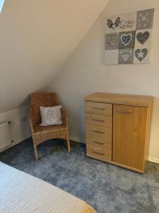 a bedroom with a dresser and a chair with a pillow at Ferienwohnung Seestern-Ranch in Niederlangen