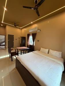 a bedroom with a bed with a ceiling fan and a table at JRR room stay in Thiruvaiyāru