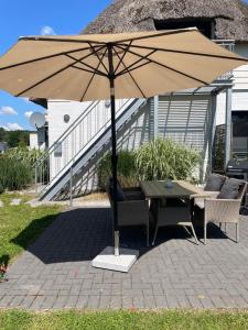 a table and chairs under an umbrella on a patio at Burgerblick in Brodersby