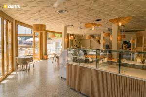 a restaurant with a counter with tables and chairs at Sènia Botànic Bonavista in Calella