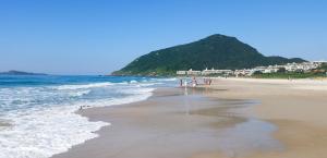 un grupo de personas caminando por la playa en Residencial Gralha Azul en Florianópolis