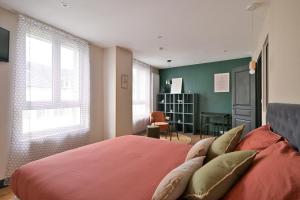 a bedroom with a red bed with green walls and windows at Brunhilde in Montivilliers