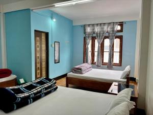 a bedroom with two beds and blue walls at Tenzin Homestay in Dirang Dzong