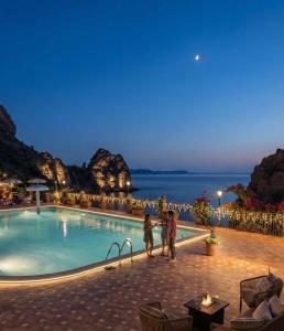 a couple standing by a swimming pool at night at La Rosa dei venti in Nebida