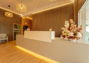a lobby with a reception counter with flowers on it at Lena Village - Hotel and Spa in Mortágua +50 photos