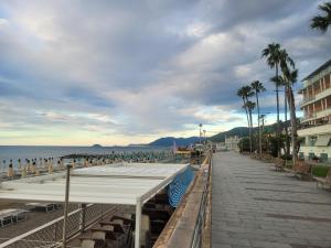 a beach with benches and palm trees and the ocean at Appartamento vacanze Loano in Loano