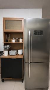 a stainless steel refrigerator in a kitchen with plates at Apartamento Completo Próximo a BR in Biguaçu