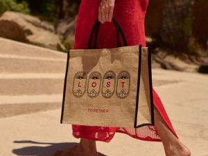 a woman holding a paper bag with four shoes on it at Golden Milos Beach Ηouse by Domotel in Provatas