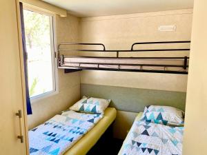 two bunk beds in a small room with a window at Mobilehome Adams Glamping - Camp Adriatic in Primošten +30 photos