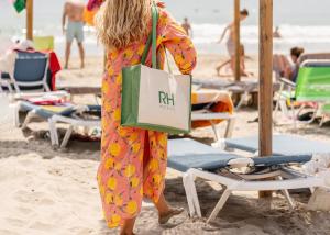 Eine Frau, die mit einer Einkaufstasche am Strand entlanggeht in der Unterkunft RH Silene Hotel & Spa 4 Sup in Castellón de la Plana